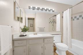 A white bathroom with a sink, mirror, toilet, and bathtub.