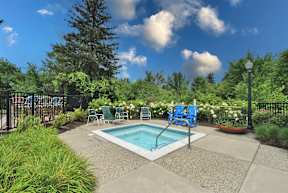 A small pool surrounded by a fence and chairs.