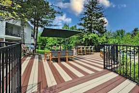 A wooden deck with chairs and a green umbrella.