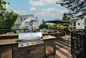 A backyard with a grill and a pool.