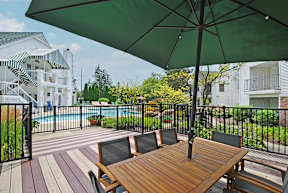 A patio with a table and chairs under a green umbrella.