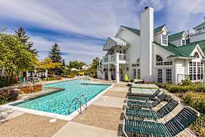 a swimming pool with lounge chairs in front of a house