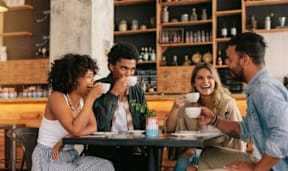 Four people are sitting at a table in a cafe.
