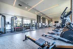 a gym with weights and cardio equipment and windows