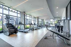 a gym with cardio equipment and windows in a building