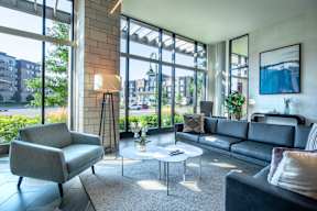 a living room with couches and chairs and large windows