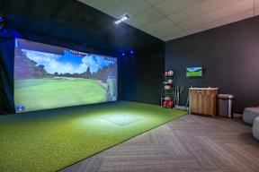 a room with a projector screen and a golf game on the wall