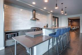 a kitchen with a long island with bar stools and a stove and a microwave