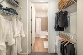 a walk in closet filled with clothes and a door to a bathroom
