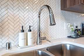 a kitchen sink with two bottles on the counter next to a faucet