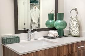 a bathroom sink with green vases and a mirror
