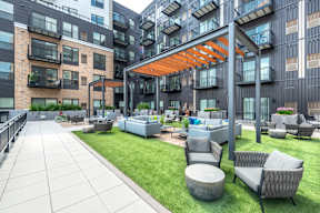an outdoor lounge area with couches and tables in front of an apartment building