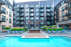a swimming pool in front of an apartment building with a pool and lounge chairs