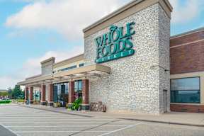 the exterior of a foods store with a brick facade and a green sign