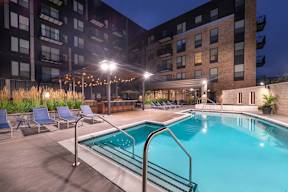 a swimming pool at night in front of an apartment building