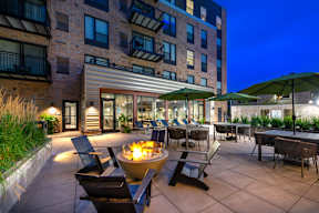 an outdoor patio with chairs and a fire pit at night