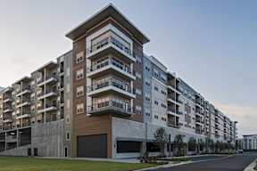 A modern apartment building with multiple balconies and garage doors.