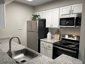 A kitchen with a stainless steel refrigerator, microwave, and oven.