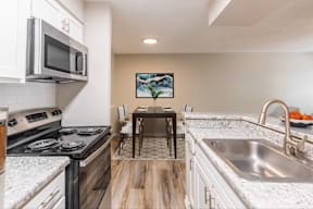 A kitchen with a stove, microwave, and sink.