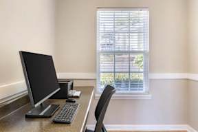 A black computer monitor sits on a desk next to a keyboard and mouse.