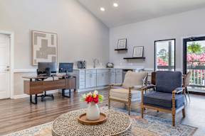 A living room with a brown coffee table and two chairs.