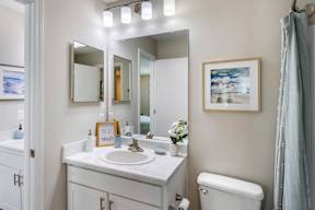 A bathroom with a toilet, sink, and mirror.