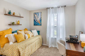 A bedroom with a yellow bed and a painting on the wall.