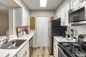 A kitchen with white cabinets and a black refrigerator.