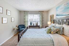 A bedroom with a large bed and a painting on the wall.