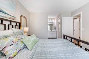 A bedroom with a bed, a lamp, and a painting on the wall.