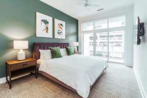 Bedroom with green accent wall and large windows at Reserve on 3rd Apartments, Birmingham, AL