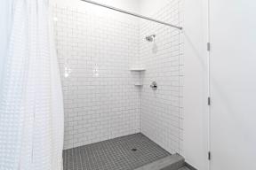 Walk in shower with white subway tile and corner shelves at Reserve on 3rd Apartments, Birmingham, Alabama
