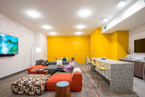Community lounge with yellow accent wall and bar seating at Reserve on 3rd Apartments, Birmingham, AL