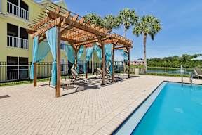 A pool area with a wooden pergola and blue curtains.