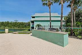 A green building with a black fence and palm trees in front.