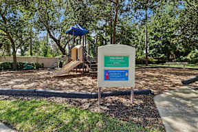 A sign in a park welcomes visitors and provides information about the park's rules.