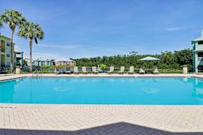 A swimming pool surrounded by palm trees and lounge chairs.