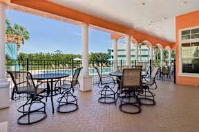 A patio with a table and chairs overlooking a pool.
