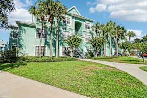 A green building with palm trees in front.