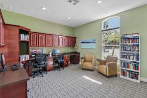 A room with a desk, chairs, and bookshelves.
