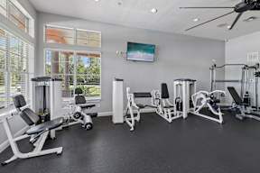 A spacious home gym with a variety of equipment and a ceiling fan.