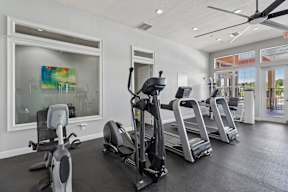 A gym with treadmills, elliptical machines, and a stationary bike.