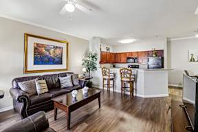 A living room with a brown leather couch, a wooden coffee table, and a painting on the wall.