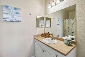 A bathroom with a white sink and a large mirror.