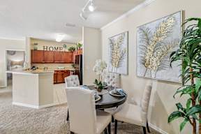 A dining room with a table set for two and a kitchen area in the background.