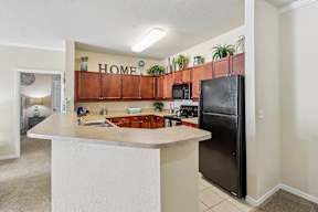 A kitchen with a refrigerator, microwave, and a counter with a sink.