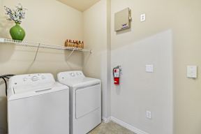 A laundry room with a washer and dryer and a shelf above them.