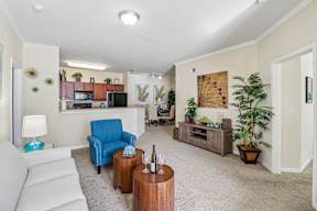 A living room with a white couch, a blue chair, and a wooden table.
