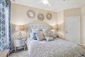 A bedroom with a patterned bedspread and a white headboard.