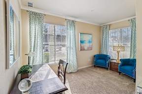 A dining room with a table, chairs, and a painting on the wall.